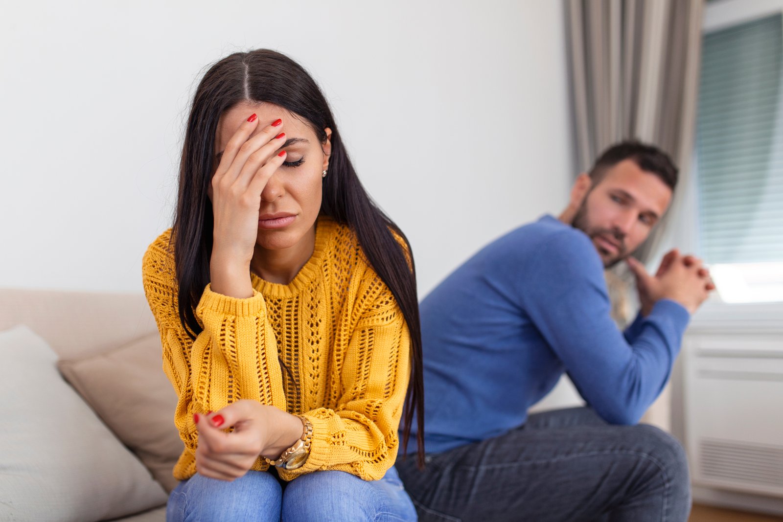 Casal em conflito no sofá, com a mulher visivelmente abalada