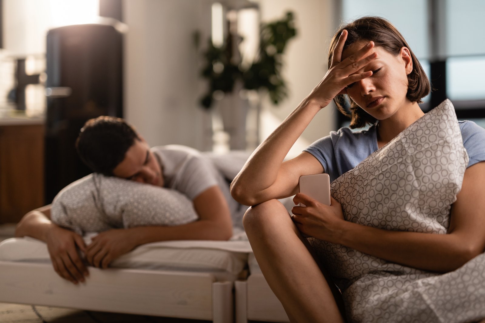Mulher angustiada enquanto o parceiro dorme ao lado